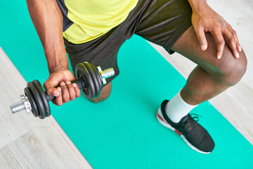 cropped view of african american man in sportswear working out with dumbbell on fitness mat at home