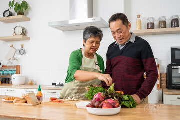 Attractive mature couple cooking foods for breakfast in kitchen with happiness