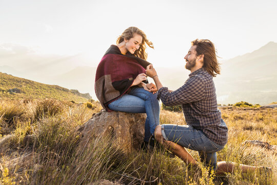 Man proposing to a woman while hiking in the hills at sunset. Franschoek, South Africa