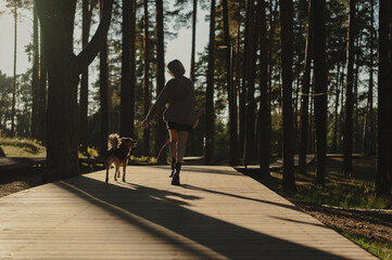 A young woman with her dog in a summer park. Happy girl walking in the woods with her mongrel dog. Concept of loving and helping dogs from a shelter.