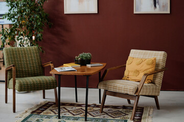 Interior of modern office with vintage furniture placed on rug with ornaments against dark red wall