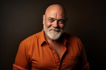 Portrait of a handsome senior man in orange shirt. Studio shot.