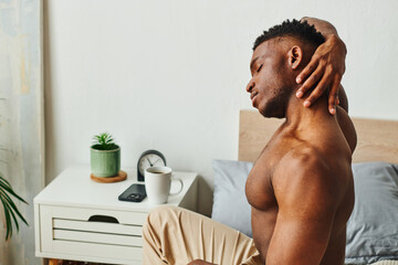 athletic shirtless man african american man stretching neck near coffee on bedside table in bedroom