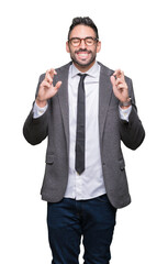Young handsome business man over isolated background smiling crossing fingers with hope and eyes closed. Luck and superstitious concept.