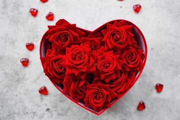 Valentine's day. Red roses and gold hearts in a heart-shaped box on a concrete background. A gift...