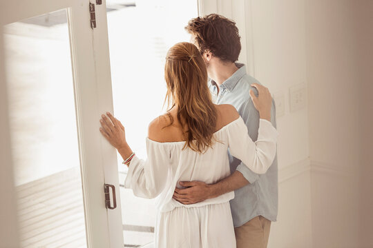 Over shoulder view of young couple looking out the window.
