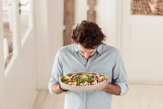 Young man looking at a beautiful salad before putting it on table.