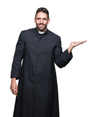 Young Christian priest over isolated background smiling cheerful presenting and pointing with palm...