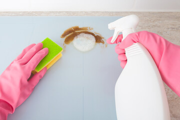 Female hands in pink rubber protective gloves holding white spray bottle and sponge and cleaning...