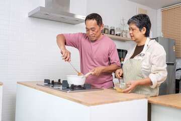 Mature asian Couples enjoy to cooking meal together in kitchen.