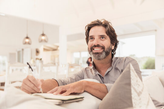 Man taking notes while hanging out in his beach house