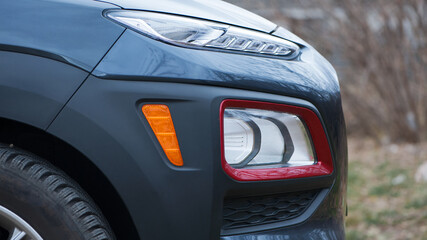 headlight of modern prestigious car closeup. beautiful headlights of a car. dark gray color, red...