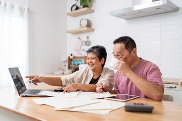 Fototapeta na wymiar Happy Asian senior couple use digital technology device to working at home