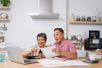 Happy Asian senior couple use digital technology device to working at home - 711580658
