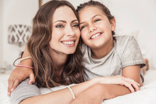 Mother and daughter having fun and goofing around in bed in a shabby chic beach house
