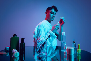 Fluid Symmetry. Seamless blend of masculinity and femininity as one half of male face transforms in neon-lit bathroom. Concept of beauty and fashion, self-care, gender equality, transformation. Ad