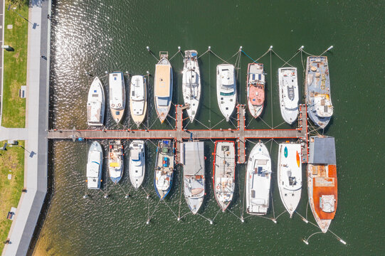 Aerial overhead view over a fleet of fishing trawlers lined up and moored along a jetty