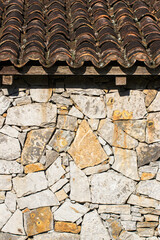 Rustic stone wall and roof with ceramic tiles.