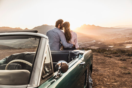 Couple enjoying a romantic moment and hugging at sunset on mountain pass with a view. Franschhoek Pass, South Africa