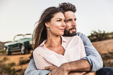 Couple enjoying a romantic moment and hugging at sunset on mountain pass with a view. Franschhoek Pass, South Africa