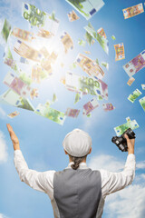 Successful young photographer with camera under dollars money rain, , demonstrating that his...