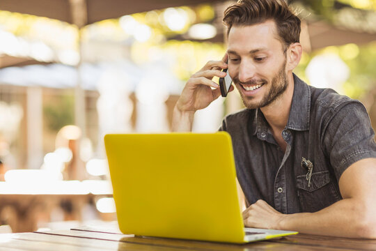 Happy guy on a laptop in an outdoor restaurant