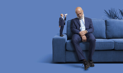Businessman sleeping and smaller version of himself waking him up