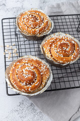 Freshly baked cinnamon buns rolls on retro metal baking rack with grey linen napkin. Traditional swedish sweet pastry kanelbulle.