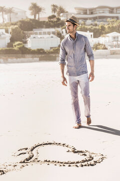 Man in pants and shirt walking and running along the beach