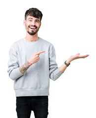 Young handsome man wearing sweatshirt over isolated background amazed and smiling to the camera while presenting with hand and pointing with finger.