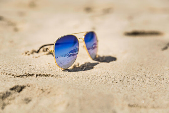 Sunglasses with reflexion lying in the sand on the beach