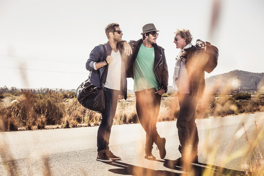 Group of guys walking along a road while hitch hiking.