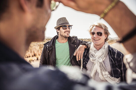Group of guys walking along a road while hitch hiking.