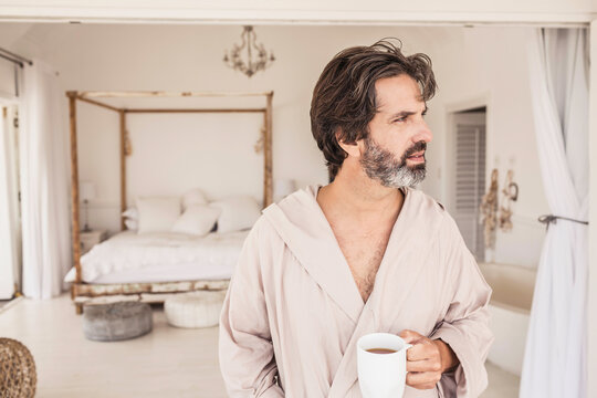 Man enjoying morning coffee in a bath robe at a beach house