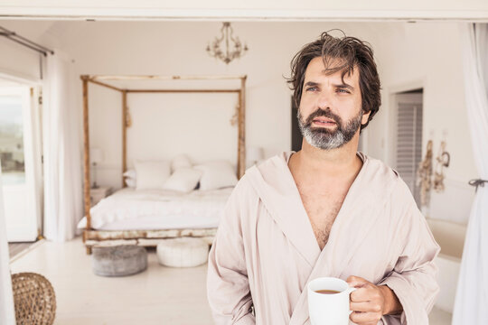 Man enjoying morning coffee in a bath robe at a beach house