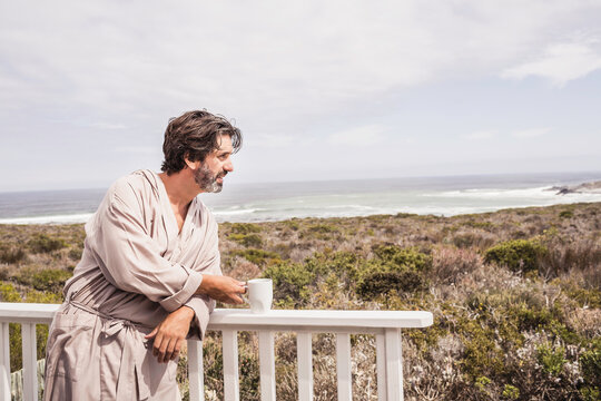 Man enjoying morning coffee in a bath robe at a beach house