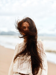 Wind-blown Beauty: Young Attractive Woman with Long Flowing Hair, Enjoying Sunny Summer Day at the Beach.