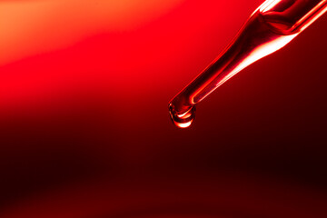 Macro science experiment, water drops, liquid dripping from glass pipette in red laboratory