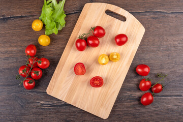 Top view of whole and cut tomatoes on a cutting board.