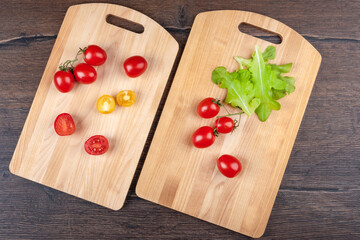 Top view of two wooden cutting boards with tomatoes and lettuce.