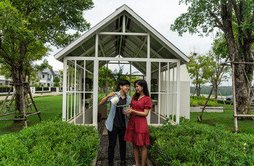 LGBT concept. A young woman wearing a red dress and a tomboy woman plant plants together and hold...