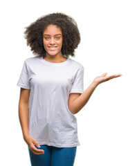 Young afro american woman over isolated background smiling cheerful presenting and pointing with...