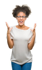 Young afro american woman wearing glasses over isolated background crazy and mad shouting and yelling with aggressive expression and arms raised. Frustration concept.