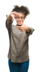 Fototapeta premium Young afro american woman wearing glasses over isolated background smiling making frame with hands and fingers with happy face. Creativity and photography concept.
