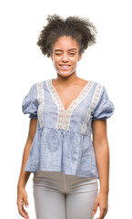Young afro american woman over isolated background winking looking at the camera with sexy expression, cheerful and happy face.