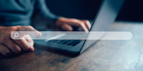 Close-up of hands typing on a laptop with a search bar graphic overlay, concept of internet...