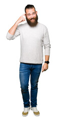 Young blond man wearing casual sweater Smiling pointing to head with one finger, great idea or thought, good memory