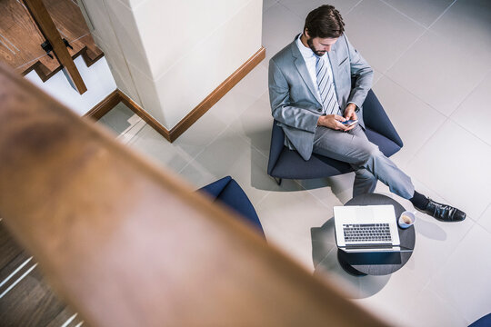 Birds eye view of business man sitting in the foyer of a building with a laptop