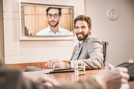 Two colleagues having a teams meeting in a conference room with third colleague