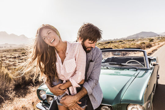 happy romantic couple having fun during a drive in the countryside with a vintage convertible